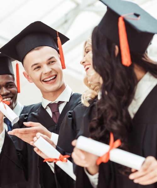 laughing graduated multiethnic students with diplomas